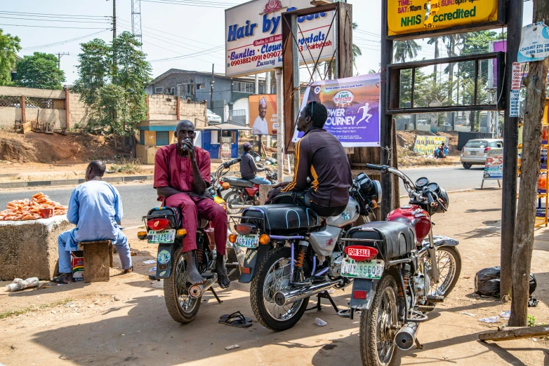 some people are standing by their motorcycles and in front of stores