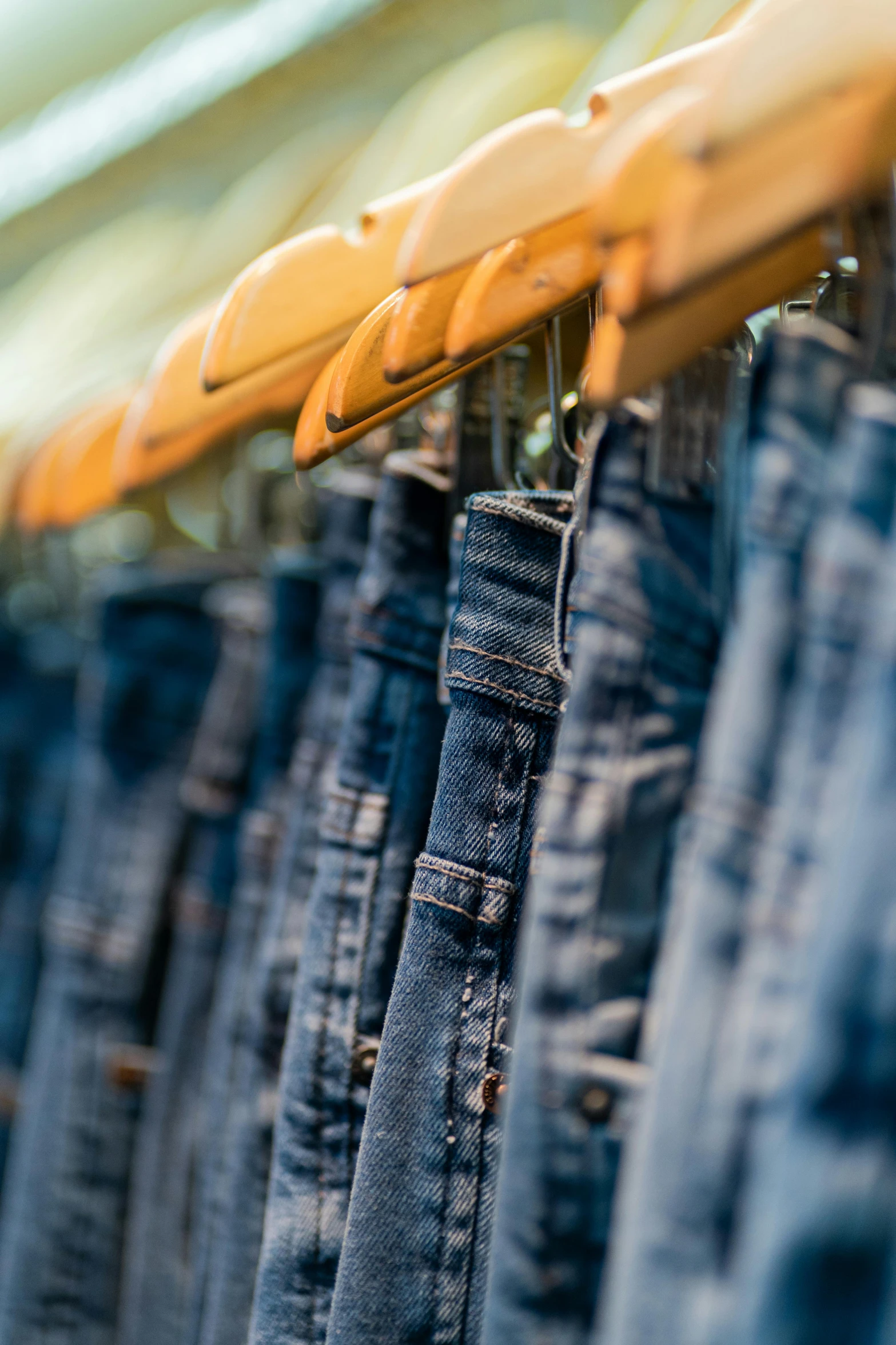 several pairs of jeans hanging on a rod