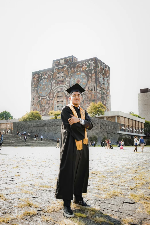 a man in cap and gown standing in front of a building