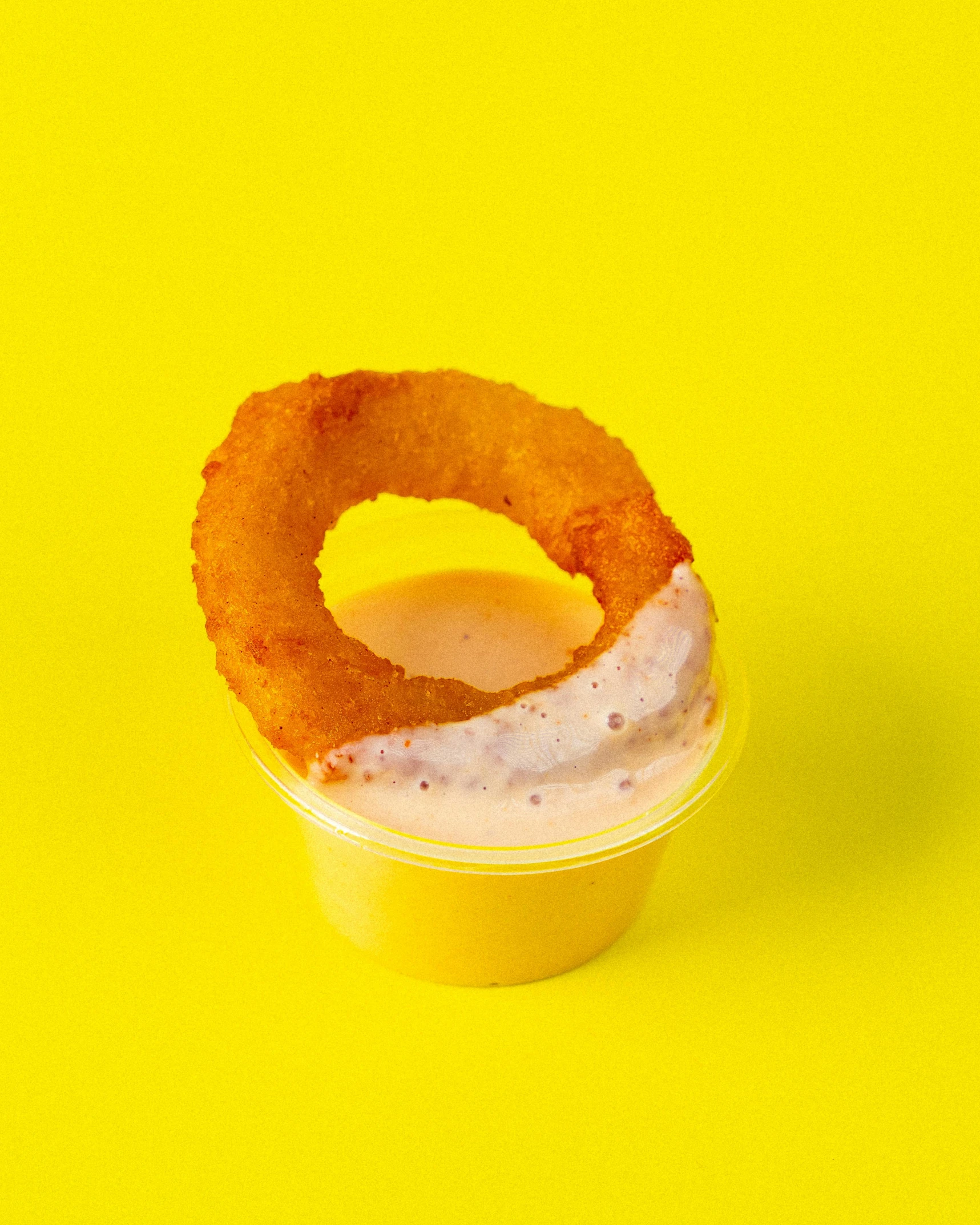 an orange doughnut sitting on top of a yellow surface