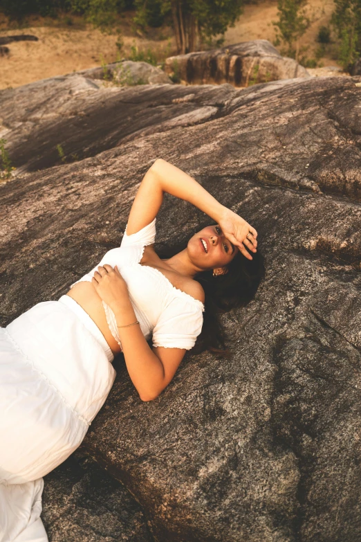 a woman laying down on top of a large rock