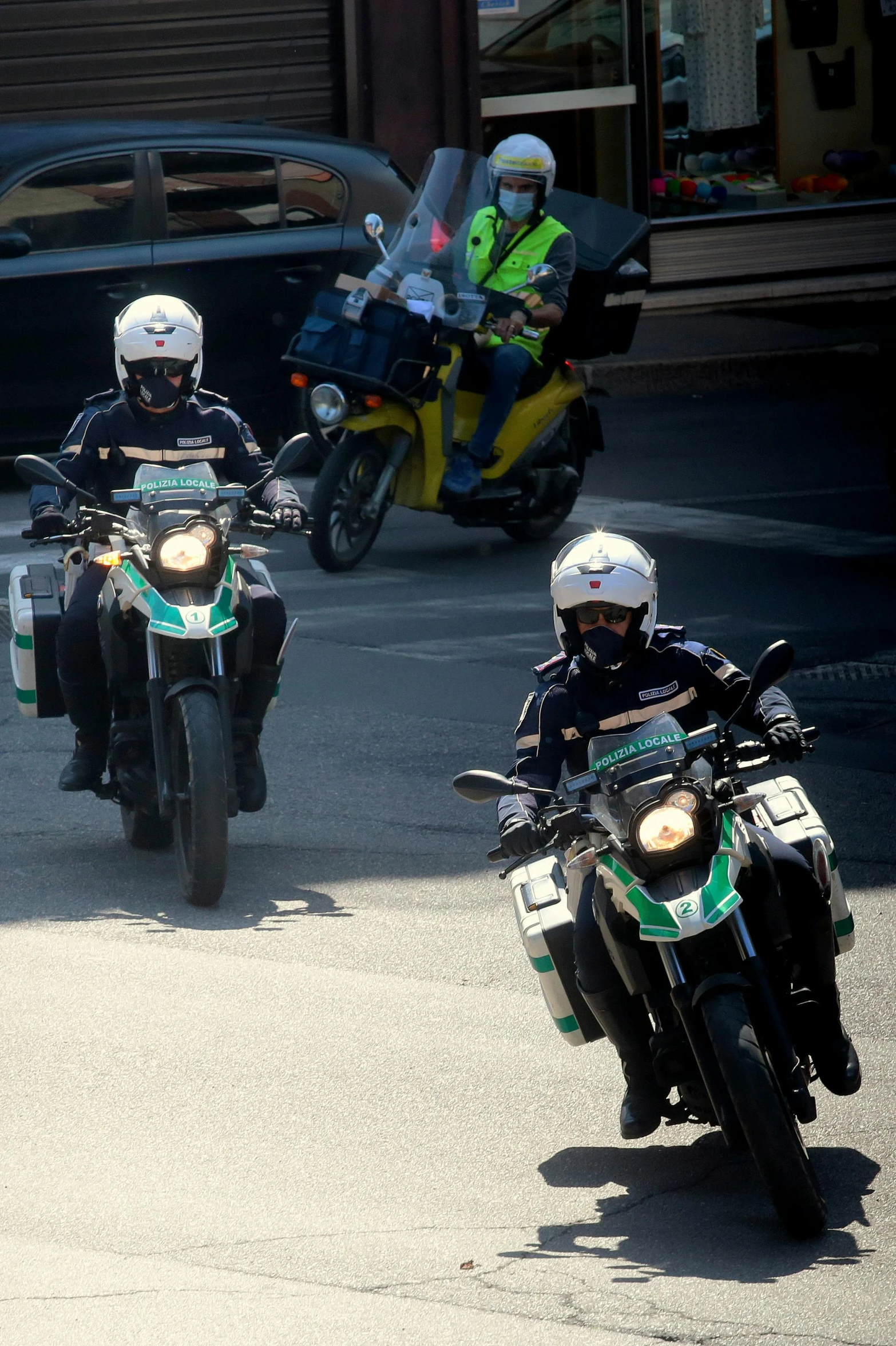 three people on motorcycles going down the street