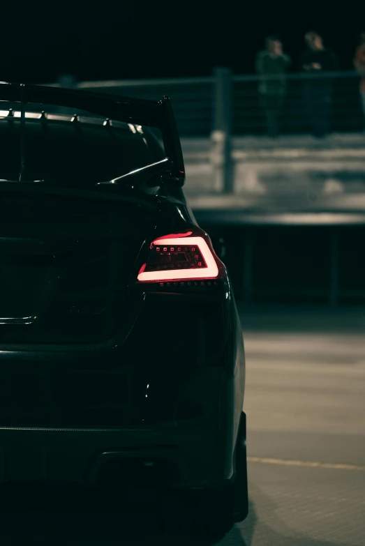 a black car parked at night near a railing