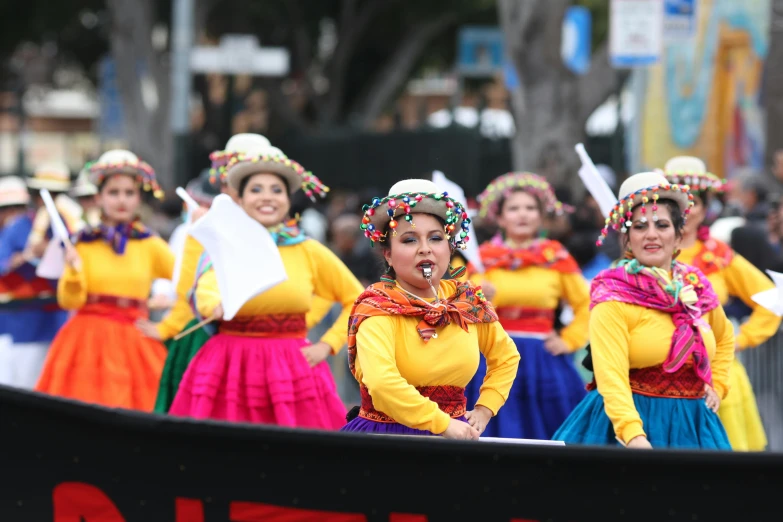 there are some colorfully dressed women performing in a parade