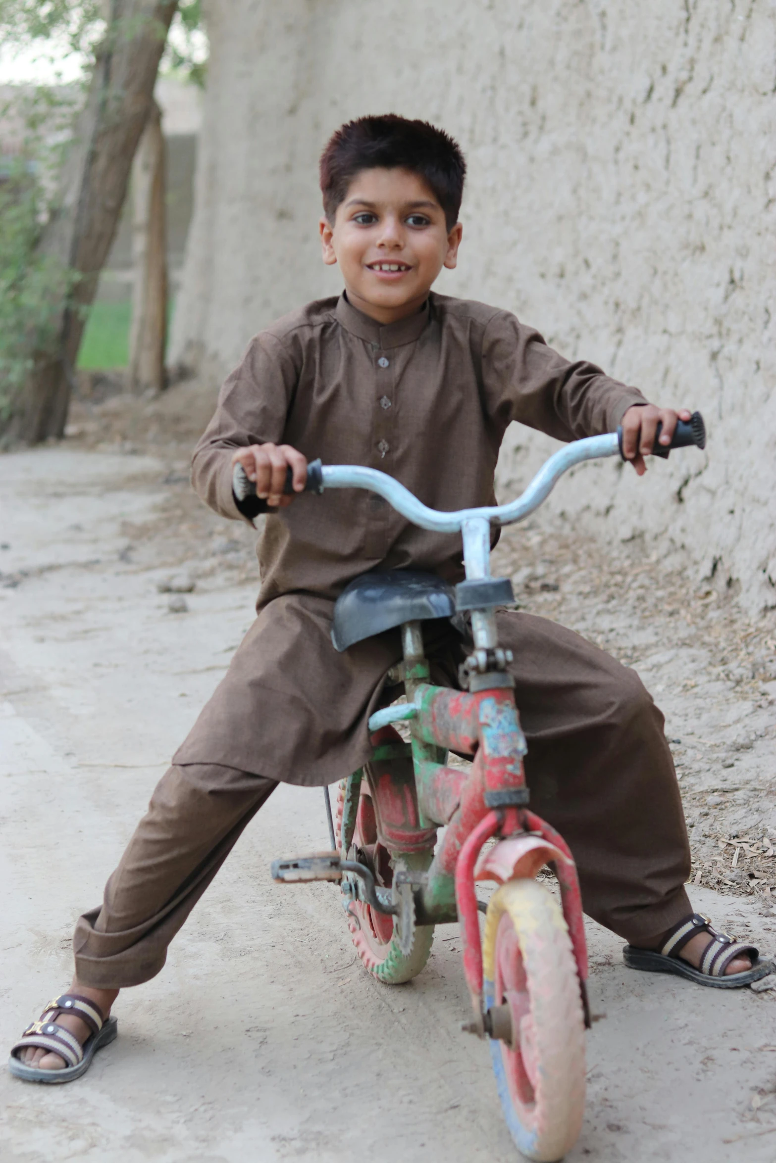 the boy in brown is sitting on his bike