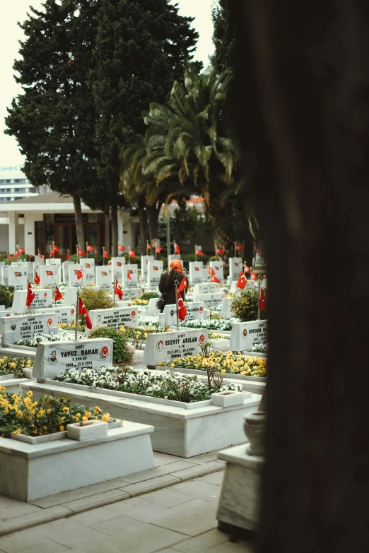 many different graves and flowers with a building in the background
