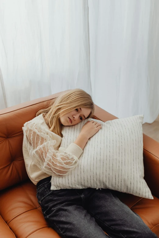 a woman sitting in a leather chair, her arms are near her face