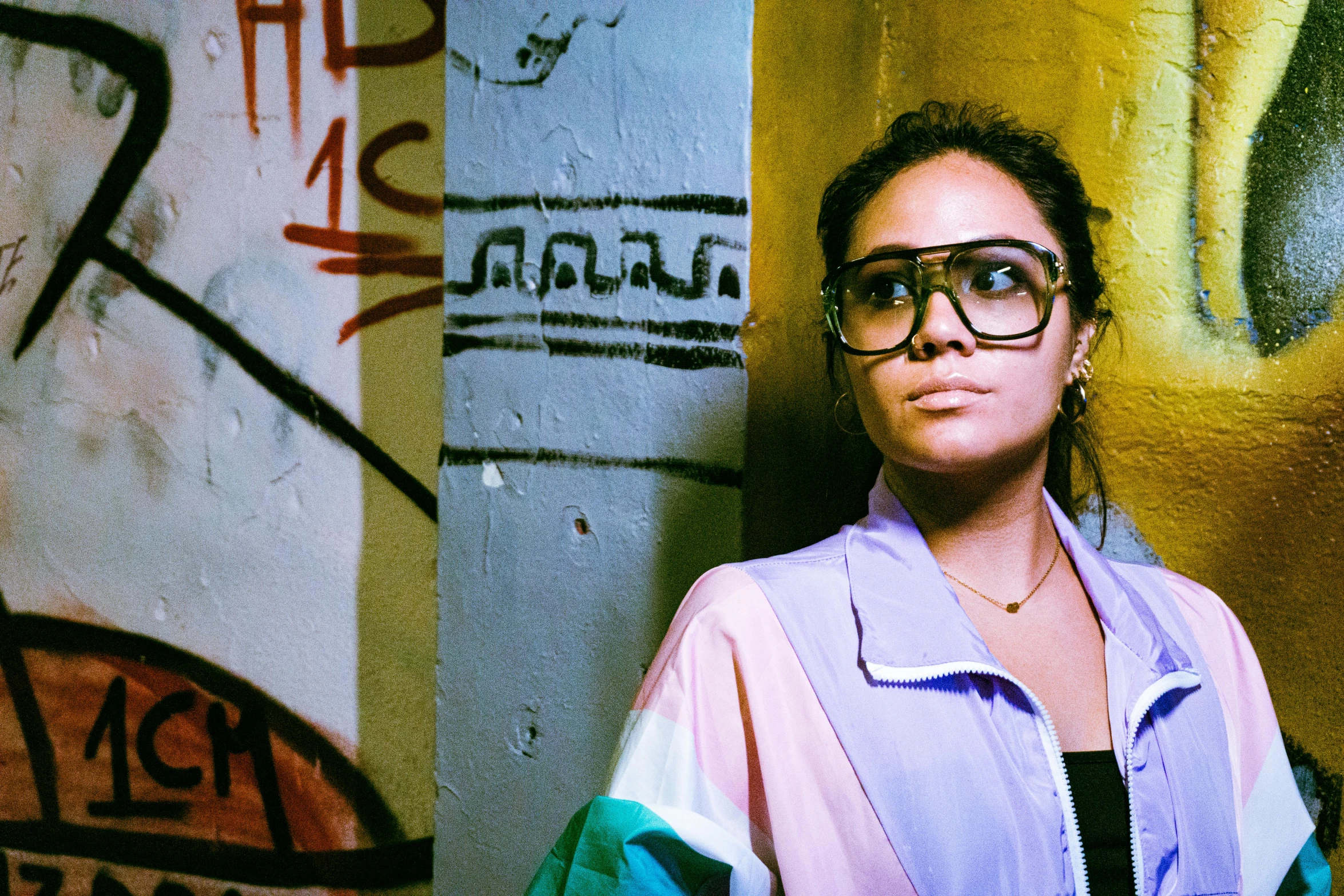 a woman standing against a wall with some graffiti on it