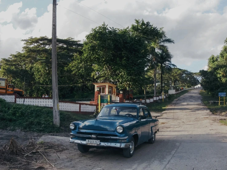 old car parked on street in front of small structure