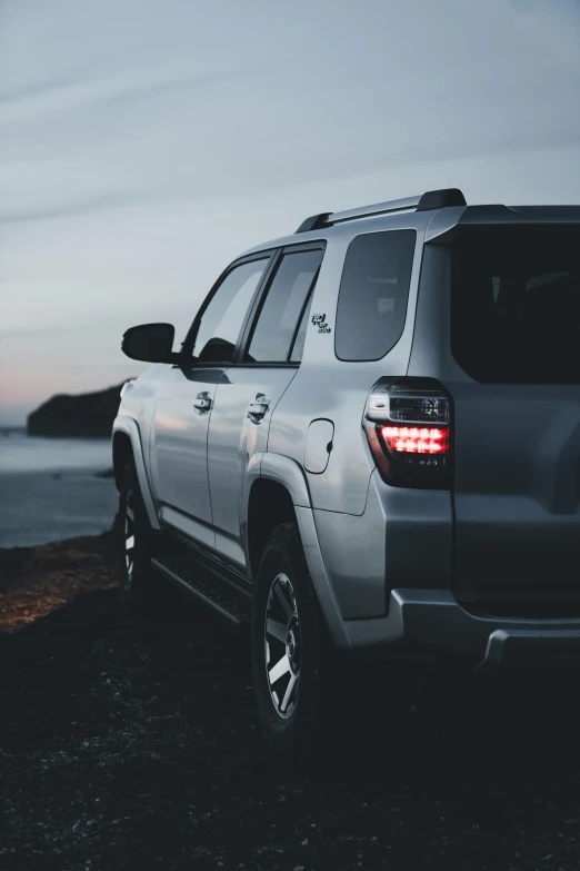 the front end of a silver toyota land cruiser parked by a body of water