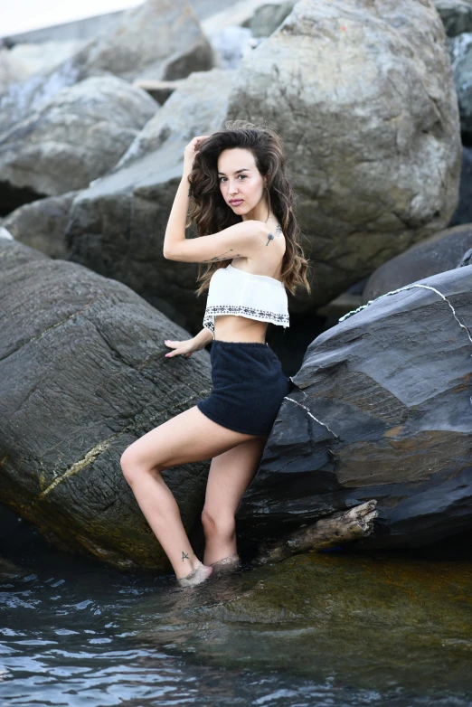 the woman in shorts is posing on the rocks