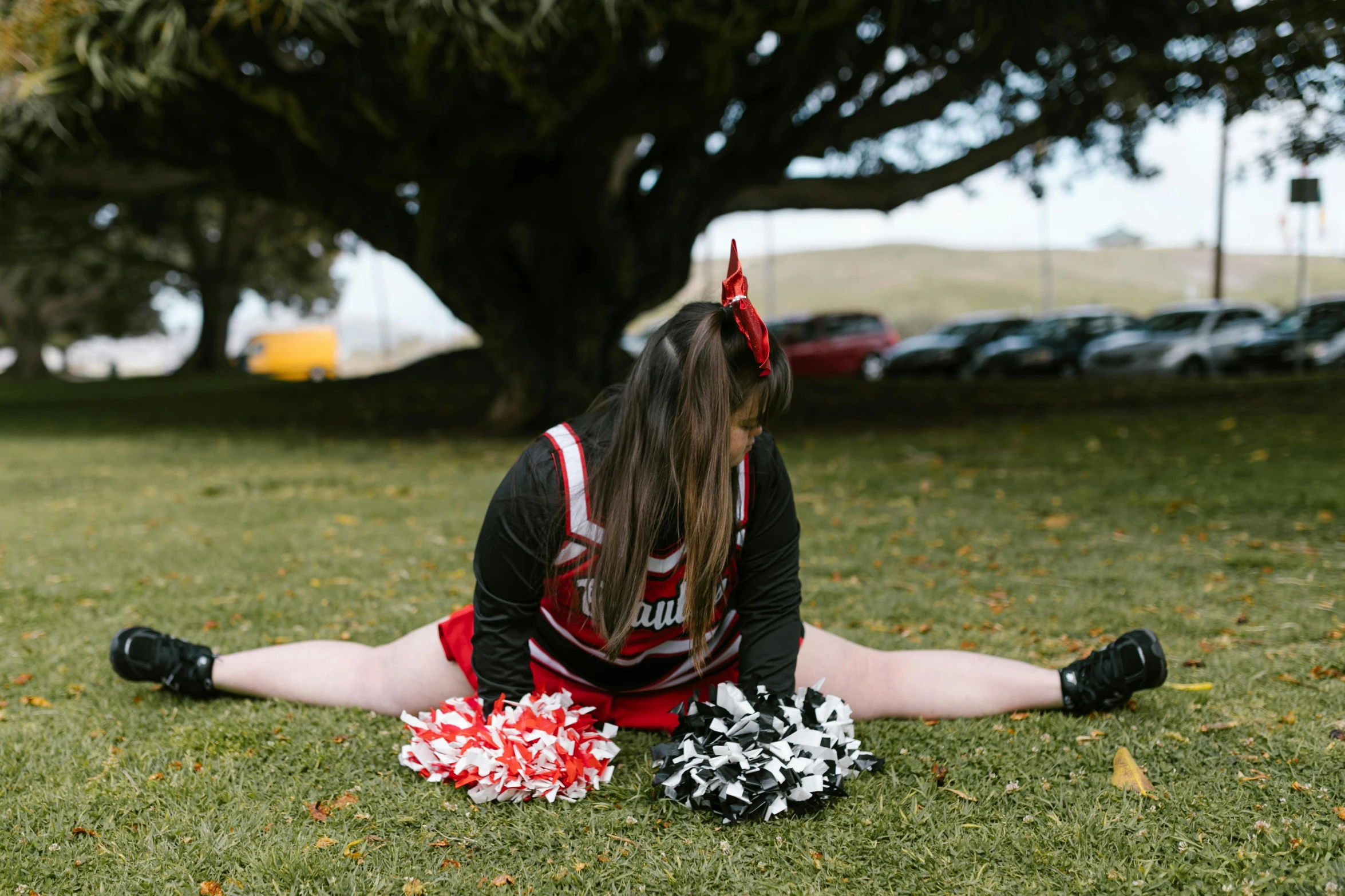 the girl is laying on the grass with some cheerleader poms