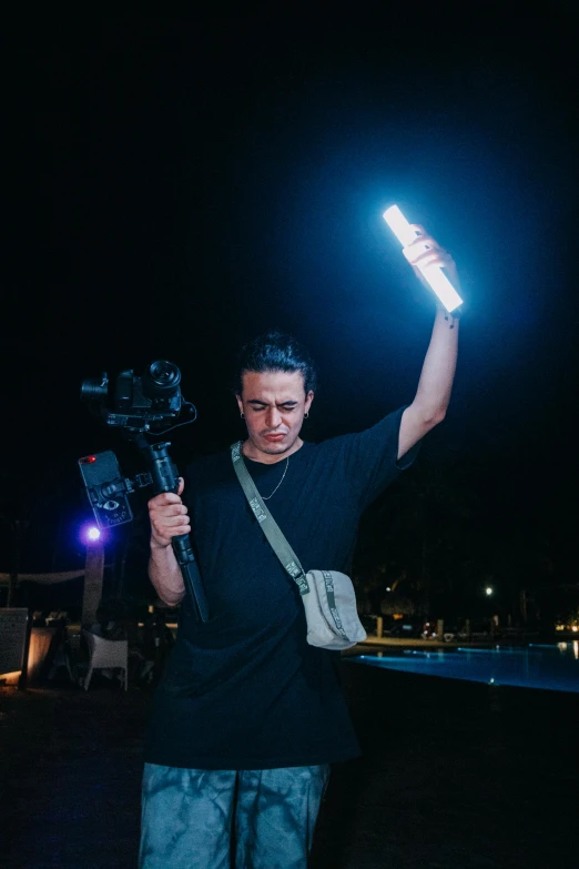 the man is holding a camera and light in the dark