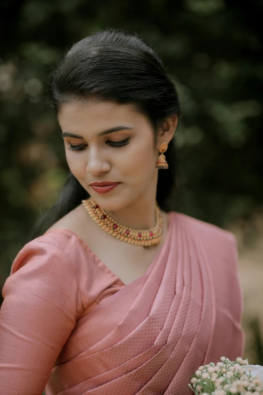 a woman holding a bouquet wearing a pink sari