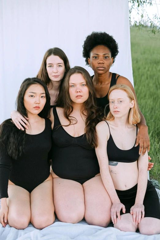 six girls in their bathing suits, posing on the bed