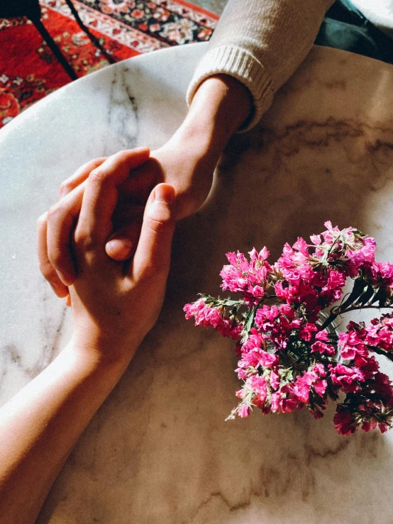 two people holding hands over a plate with flowers