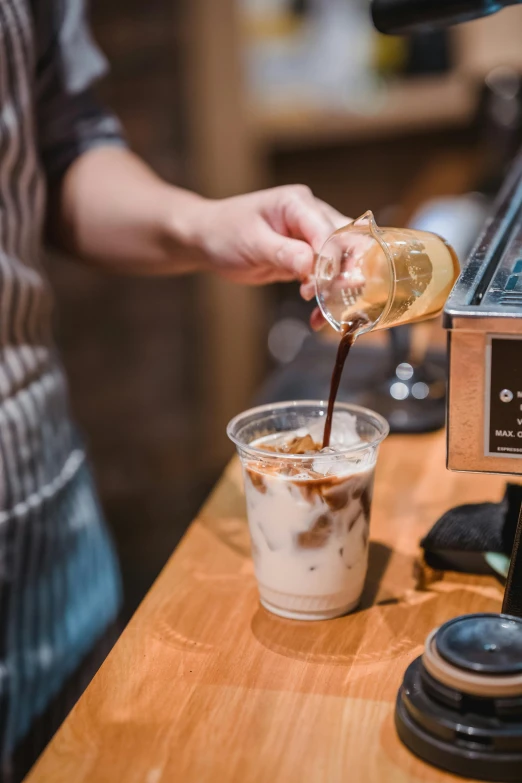 someone pouring a beverage out of a cup