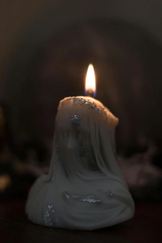 a white candle with frost on top on a table