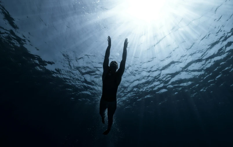 man diving under the water to catch soing