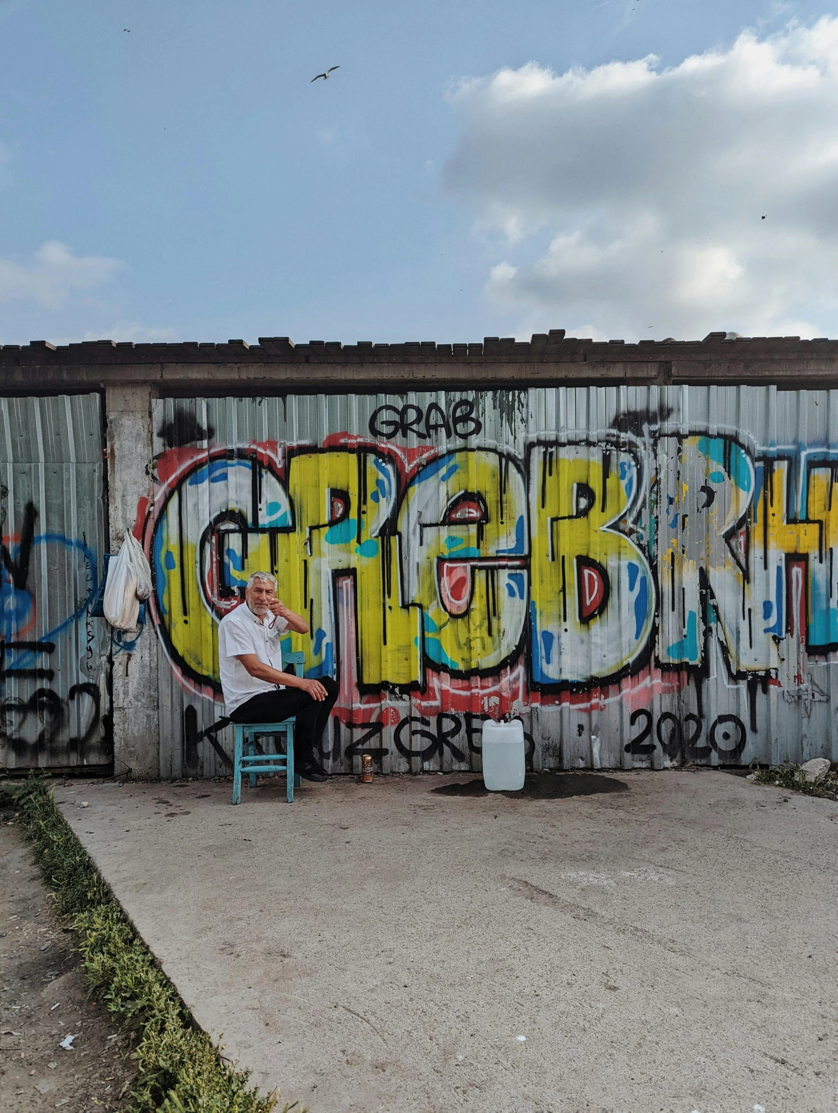 a man that is sitting on top of a chair next to some graffiti