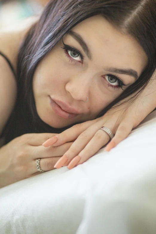 a beautiful young woman laying on top of a white sheet