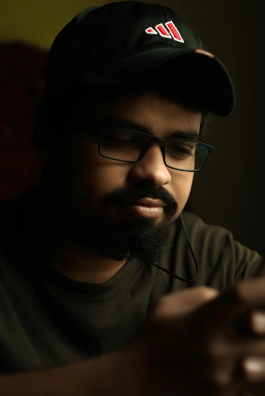 a man sitting down wearing headphones and looking at his cell phone