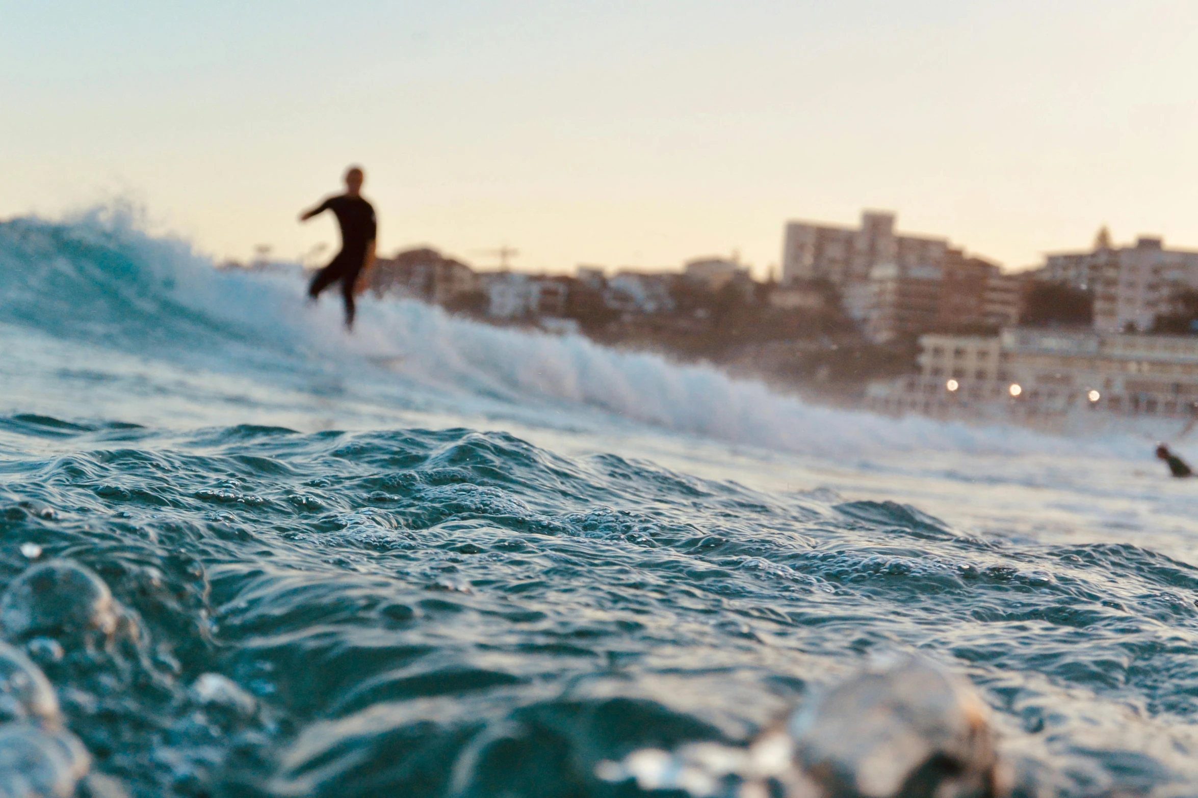 a surfer is riding the waves with some buildings in the background