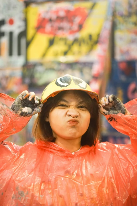 a child with a hat on their head wearing a plastic coat