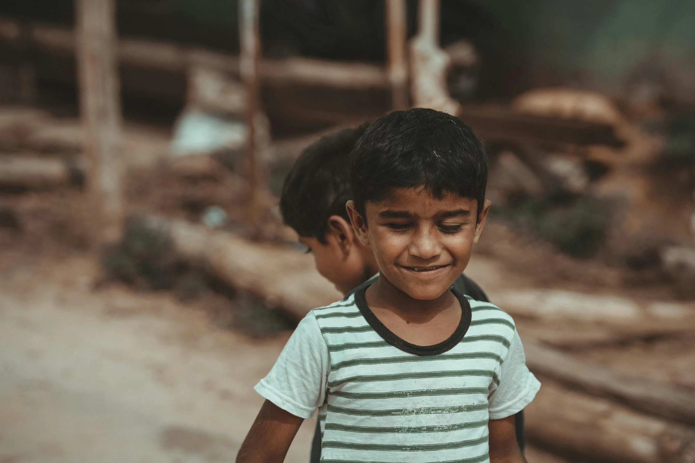 a little boy is laughing and standing in the dirt