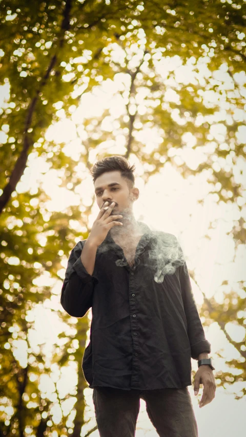 man smoking cigarette in an open area with trees