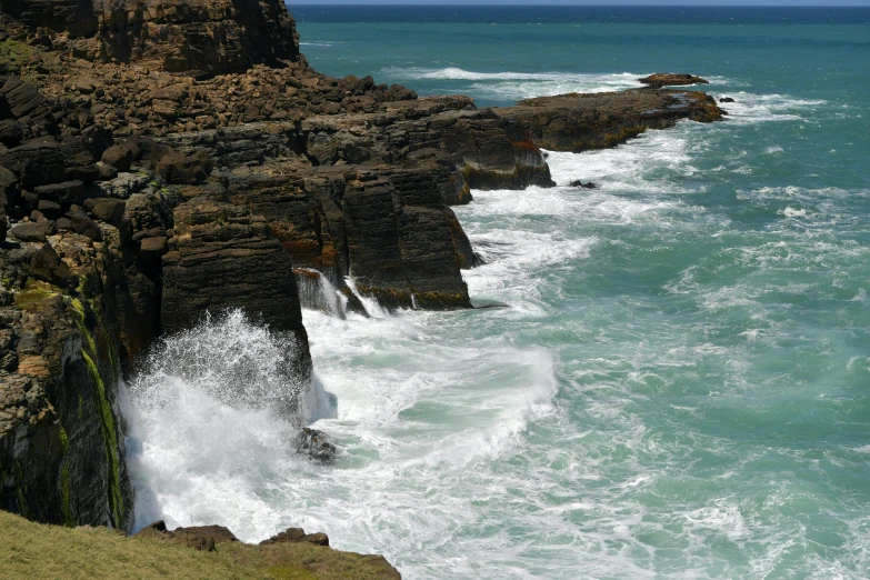 large waves crashing against rocky coastline on a clear day