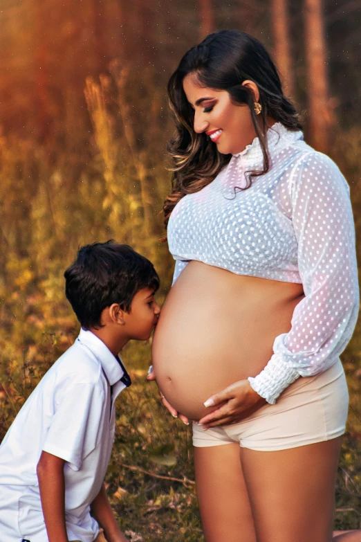 a pregnant woman poses for a po with a boy