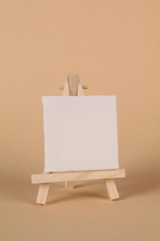an easel made out of natural wood with the white canvas on it