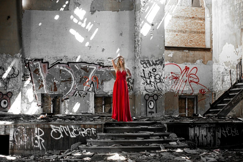 a woman in a red dress standing near a wall with graffiti