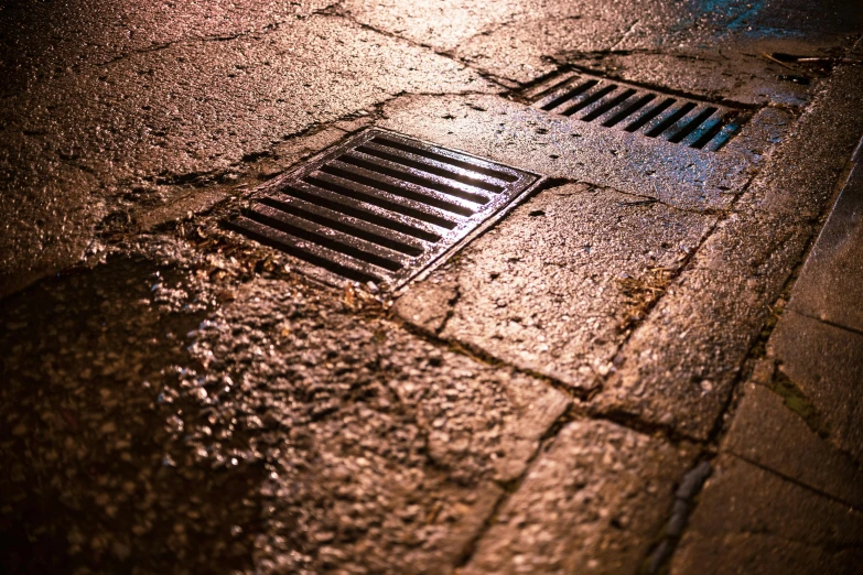 a street drain next to a sidewalk on a city street