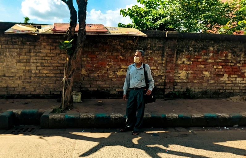 a man standing on the sidewalk in front of a wall