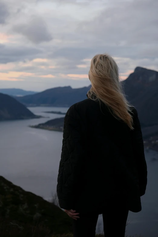 a woman looking at the sea from a hill above