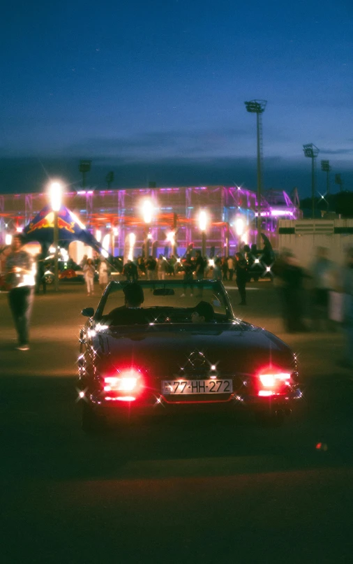 a black car driving past people in street