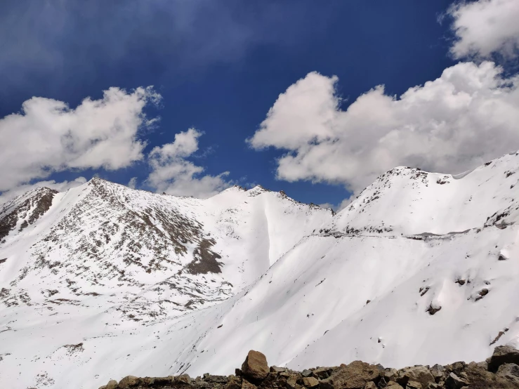 a snow covered mountain range under a cloudy blue sky