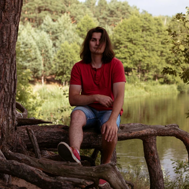 man sitting on the log with trees surrounding him