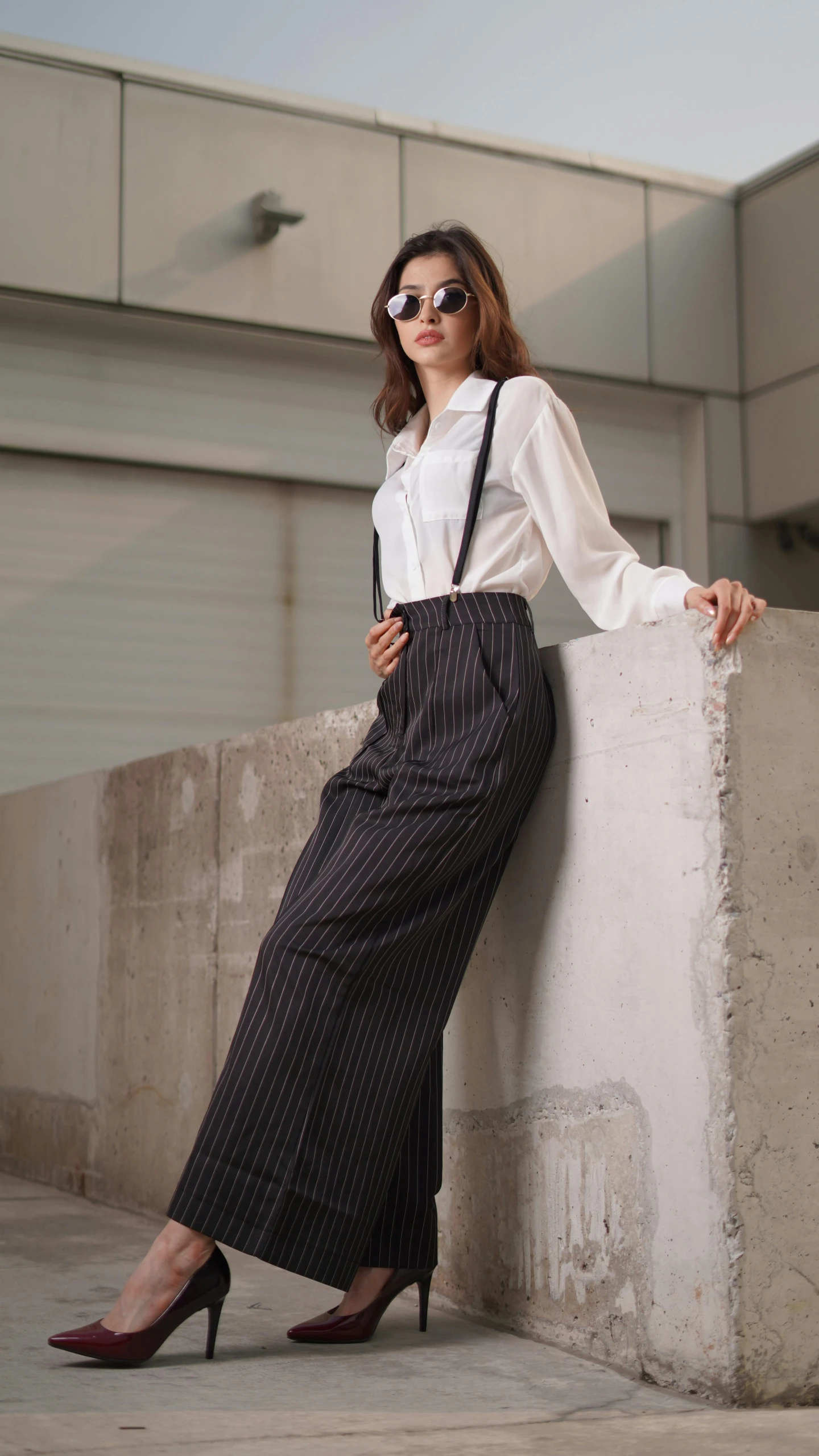 a lady leaning up against the side of a building wearing high heeled shoes