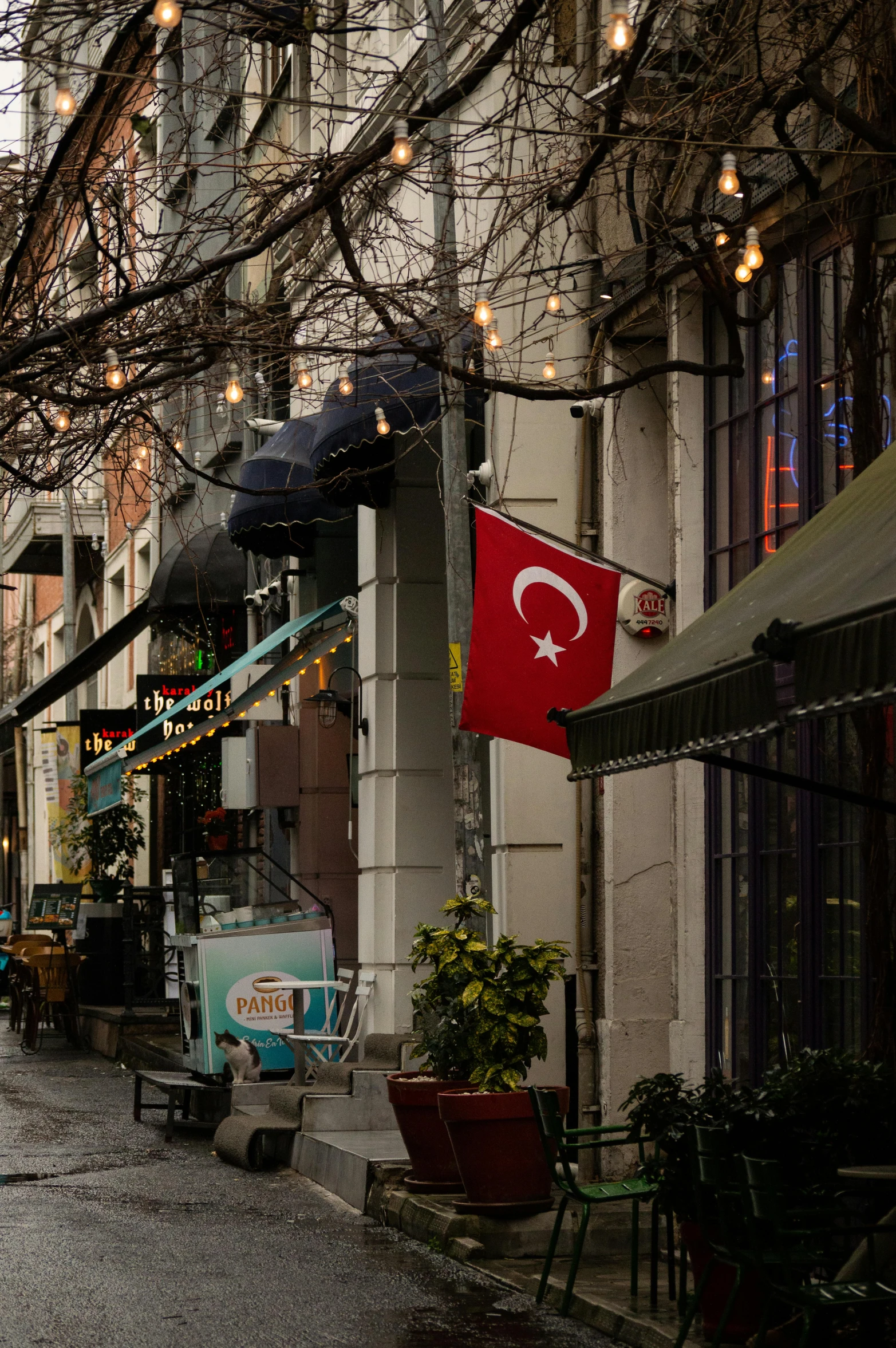 a narrow street with a few restaurants and tables