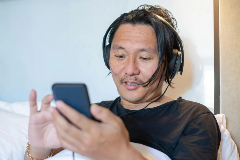 a man with headphones on while looking at his cell phone