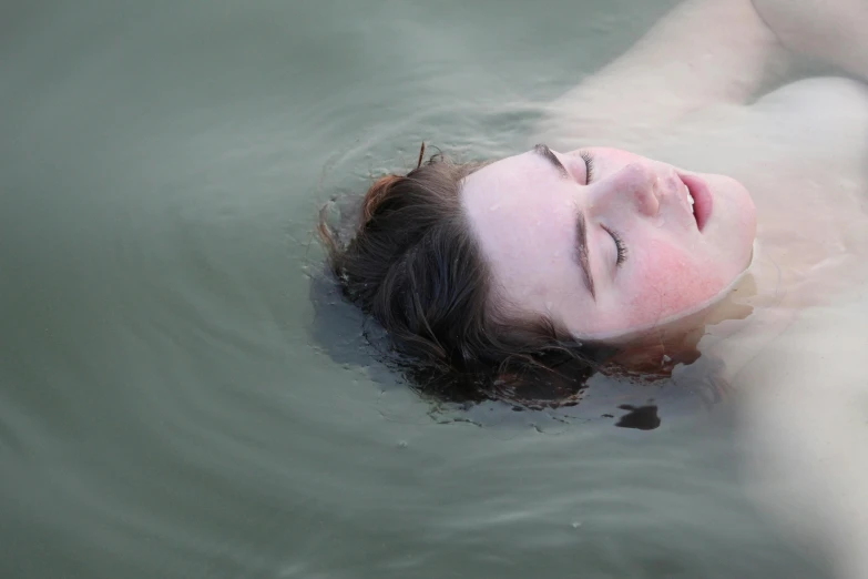 a woman laying down in water while floating