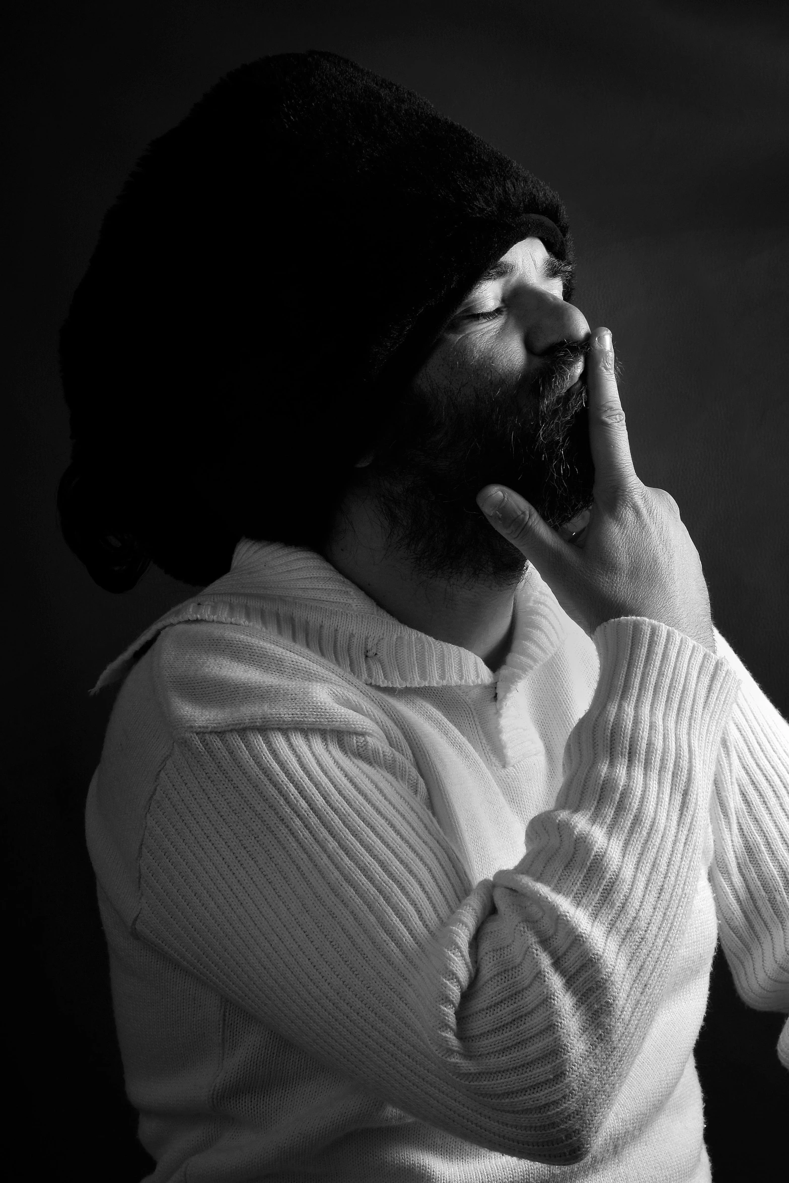 a bearded man wearing a black hat talking on a cell phone