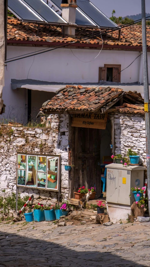 there is an old stone house with two pots and a refrigerator outside