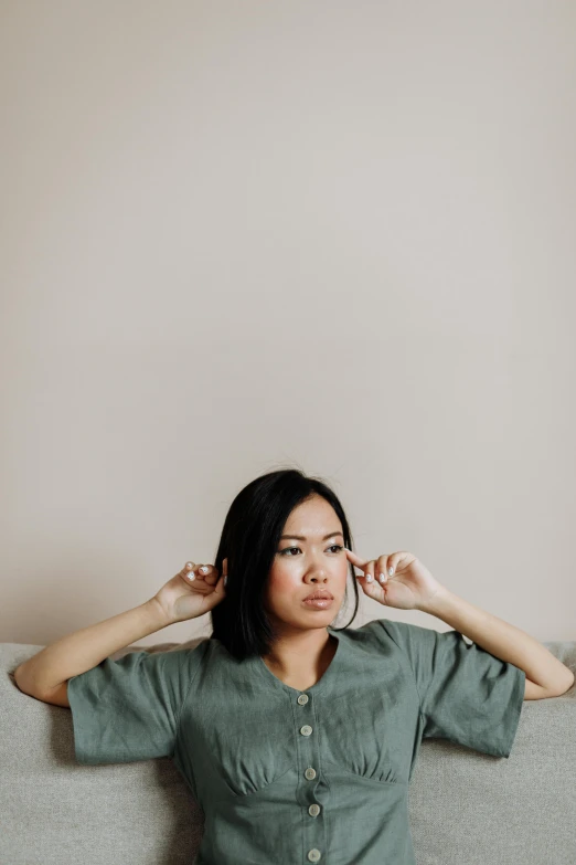 an asian woman posing while holding her hands up behind her head