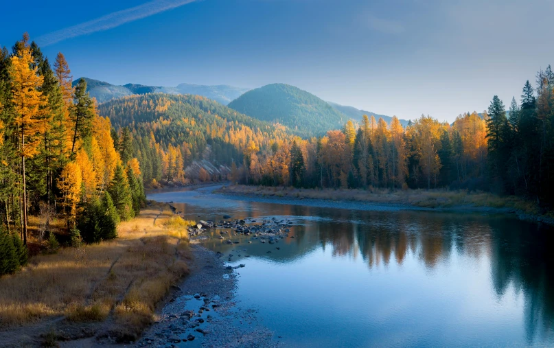 there is a calm pond surrounded by colorful trees