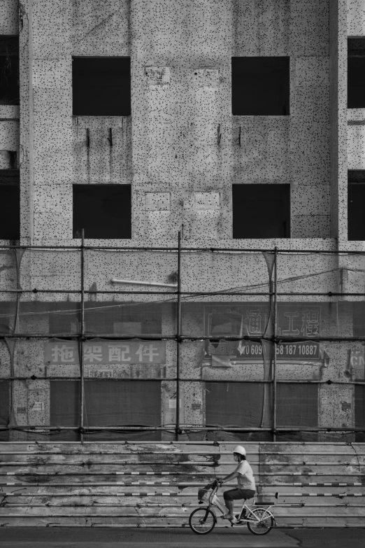 black and white image of man on bicycle on city street