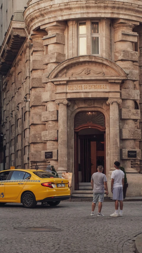 two people walk into a building with a yellow cab in front of it